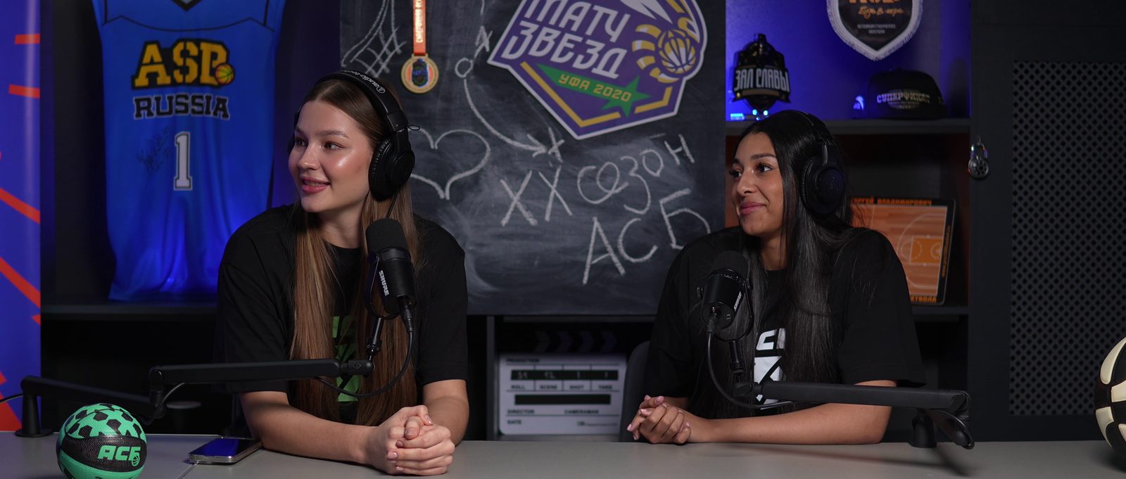 Two presenters at the sports set desk with basketball decor