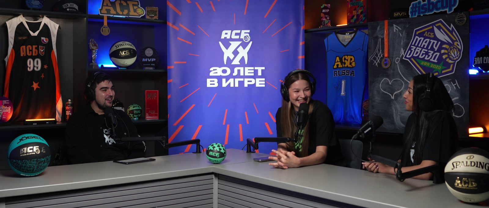 The OKVideo.Pro sports set with basketball decor: three presenters at the desk